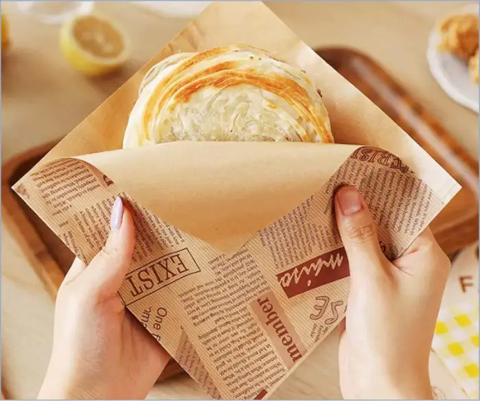 A person holding food on wrapping paper